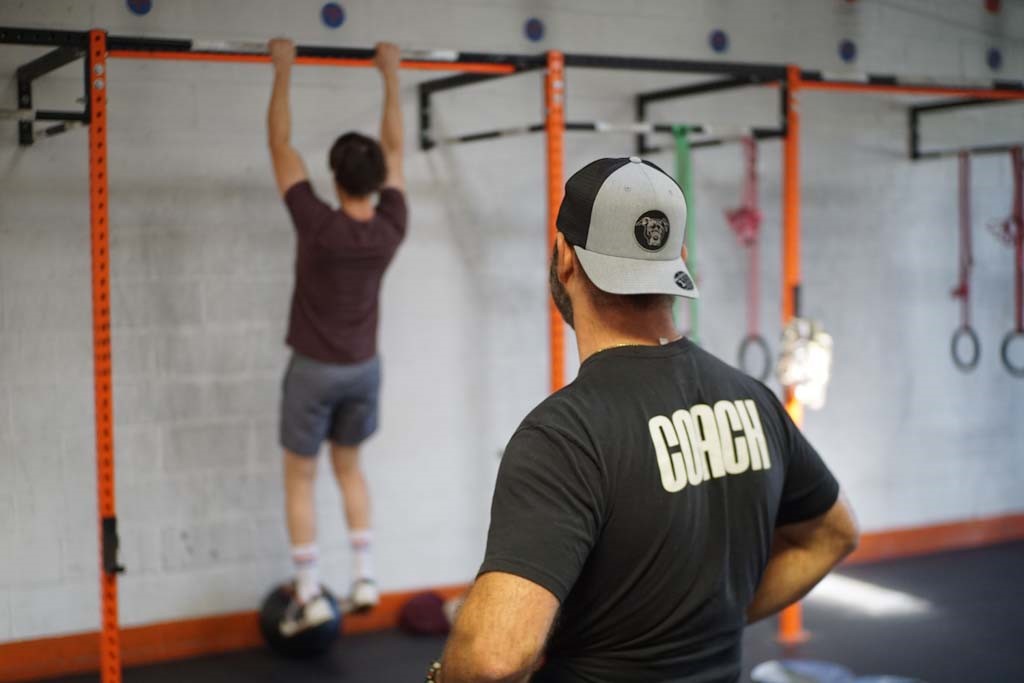 Coach watching athlete do pull-ups.