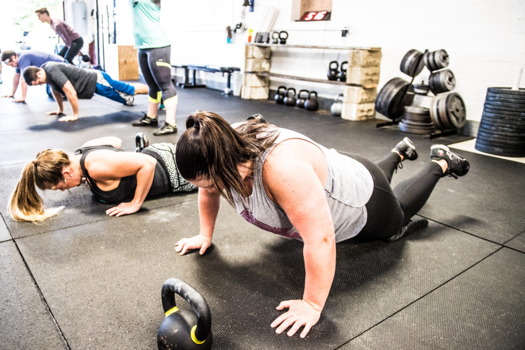 Two people are doing push ups in a gym.