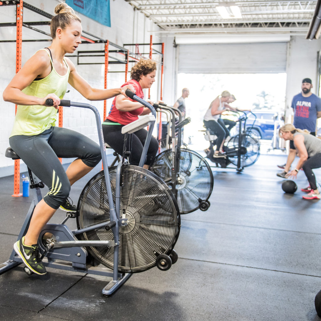 A group of people in the gym on stationary bikes.