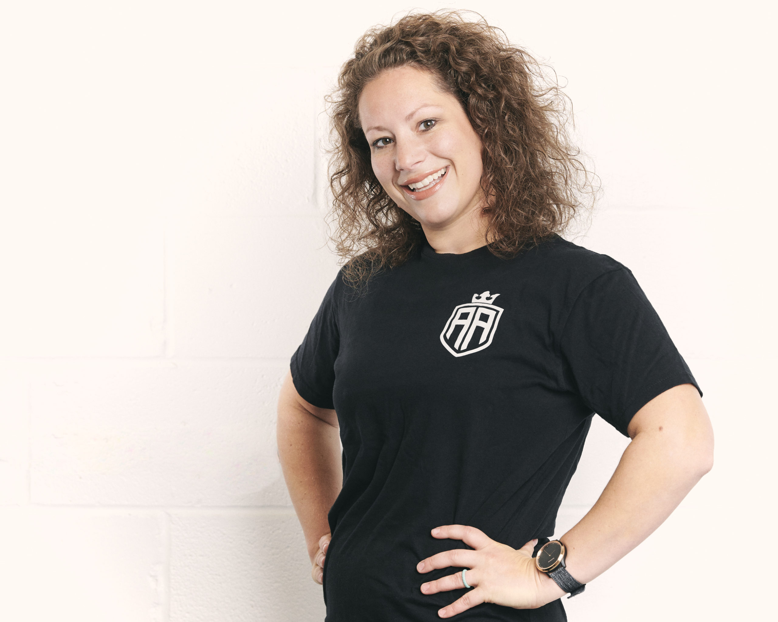 A woman in black shirt standing next to wall.