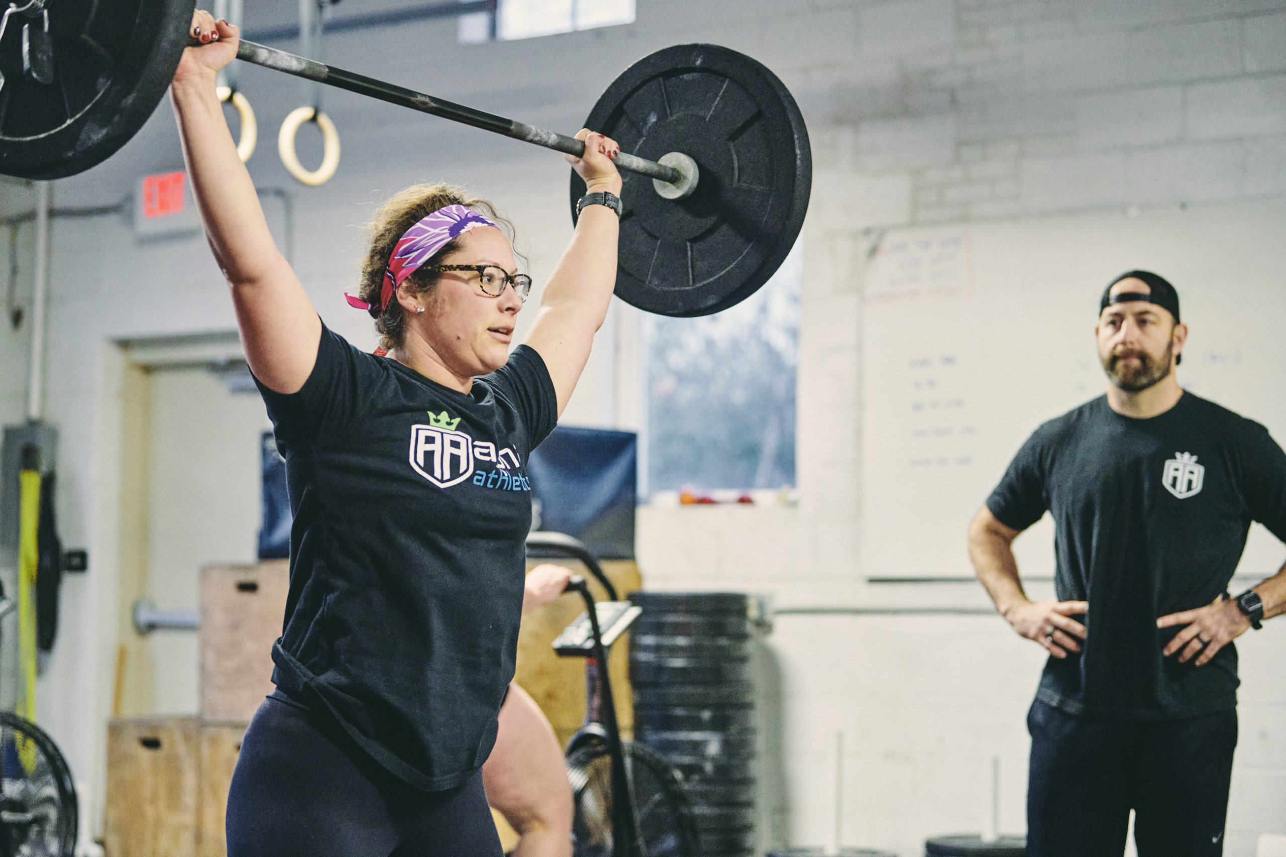 A woman holding onto a bar while standing in front of another man.