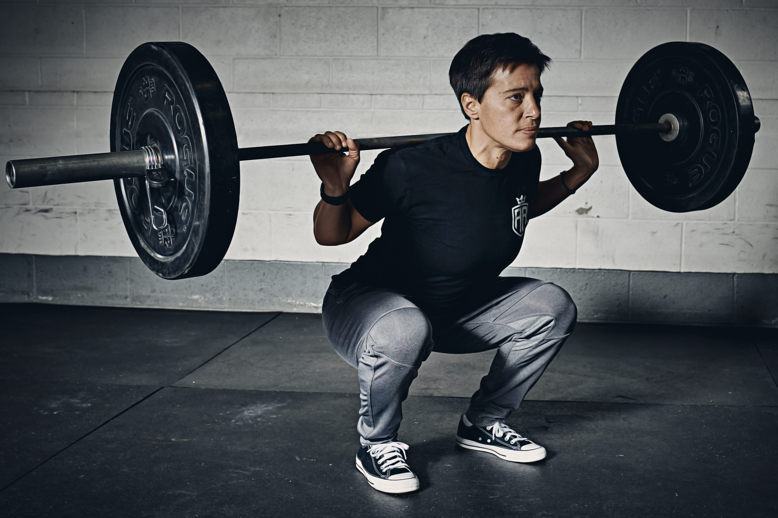 A man squatting with a barbell in his hands.